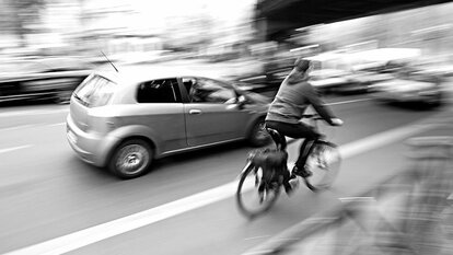 Mobilitaet, Verkehr, Radfahrer auf Radweg an Straße mit Auto