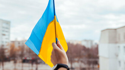 Flagge der Ukraine wird in Hand gehalten